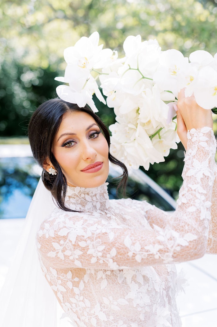 Bride holding white orchid bouquet soft light portrait