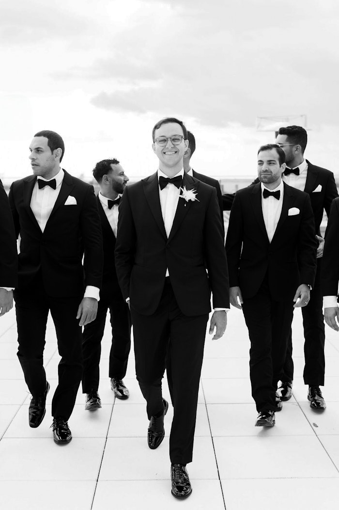 Groom walking with groomsmen modern black and white portrait
