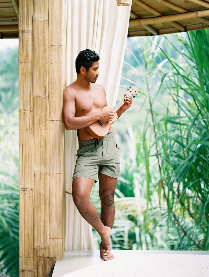 Man playing ukulele on a balcony overlooking lush Bali greenery, captured in a relaxed and cinematic lifestyle engagement session