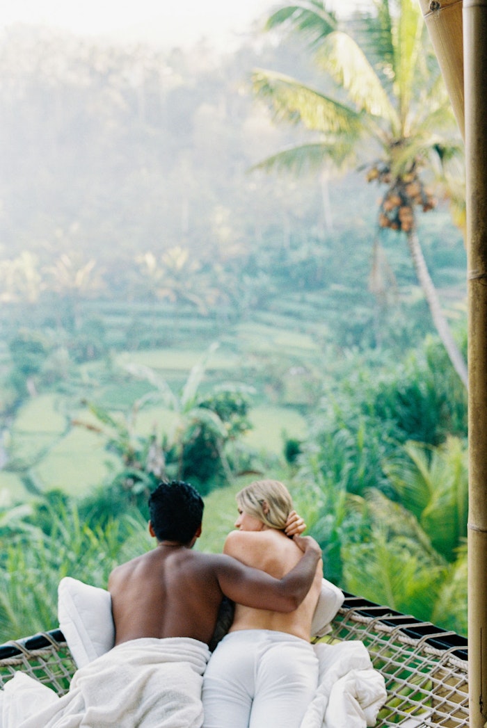 Couple sitting together overlooking lush Bali jungle landscape, captured in a peaceful and romantic engagement moment