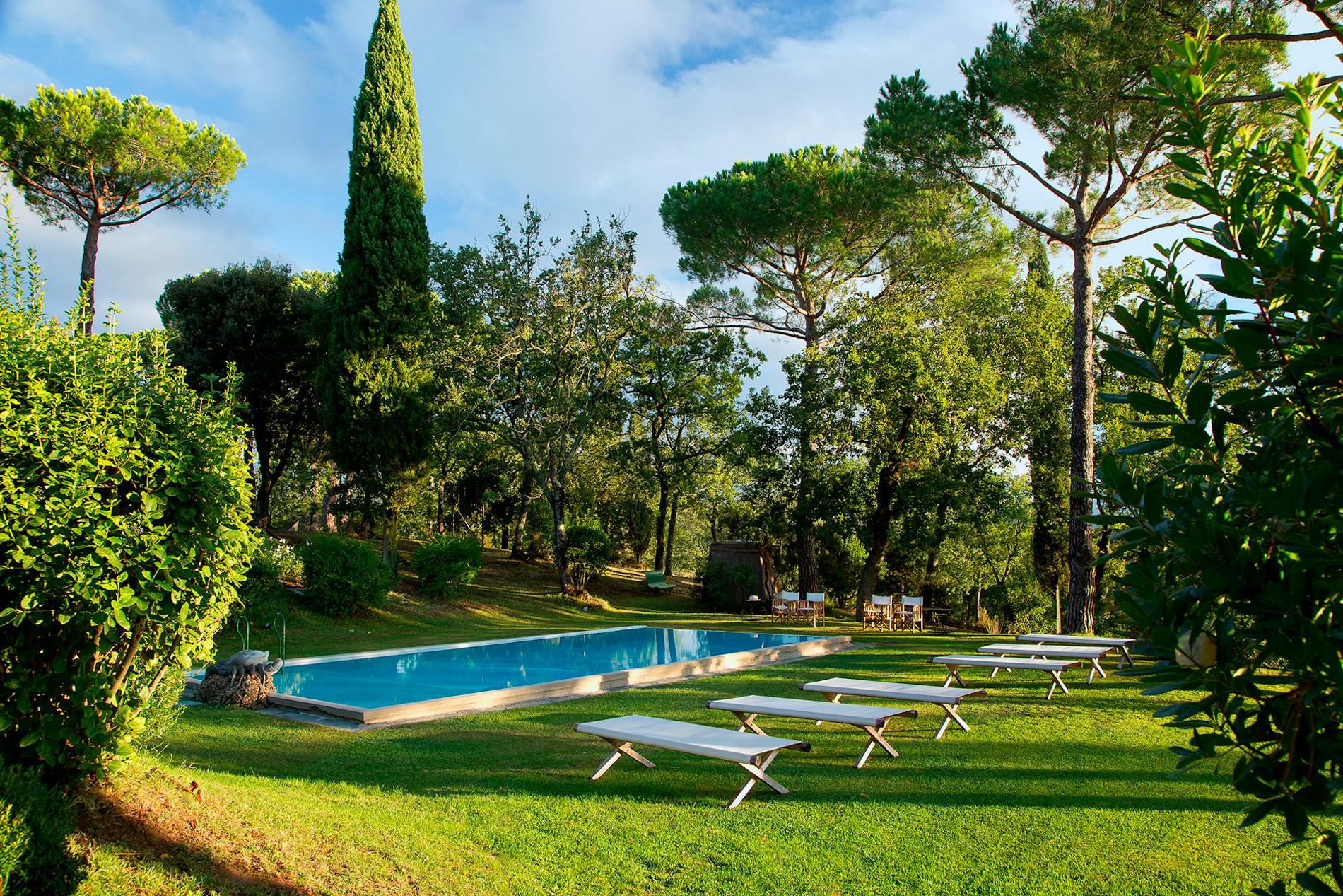 The heated swimming pool in the garden of Villa La Tavernaccia, surrounded by trees