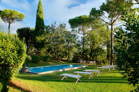 The heated swimming pool in the garden of Villa La Tavernaccia, surrounded by trees
