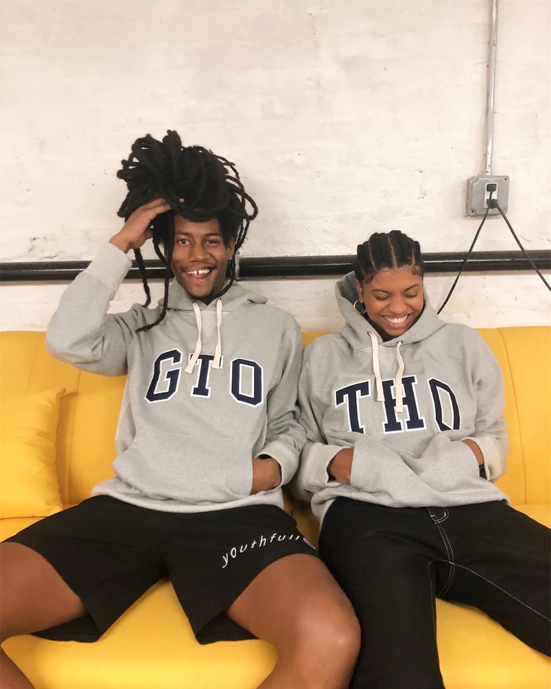 Two smiling people sitting on a couch wearing gap sweaters.