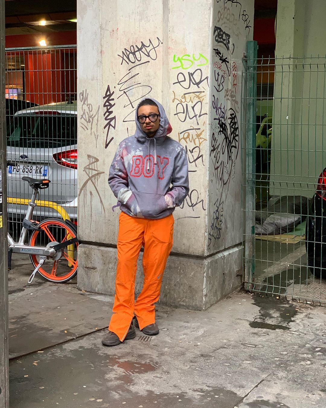 A man posing on the streets wearing a gap sweater.