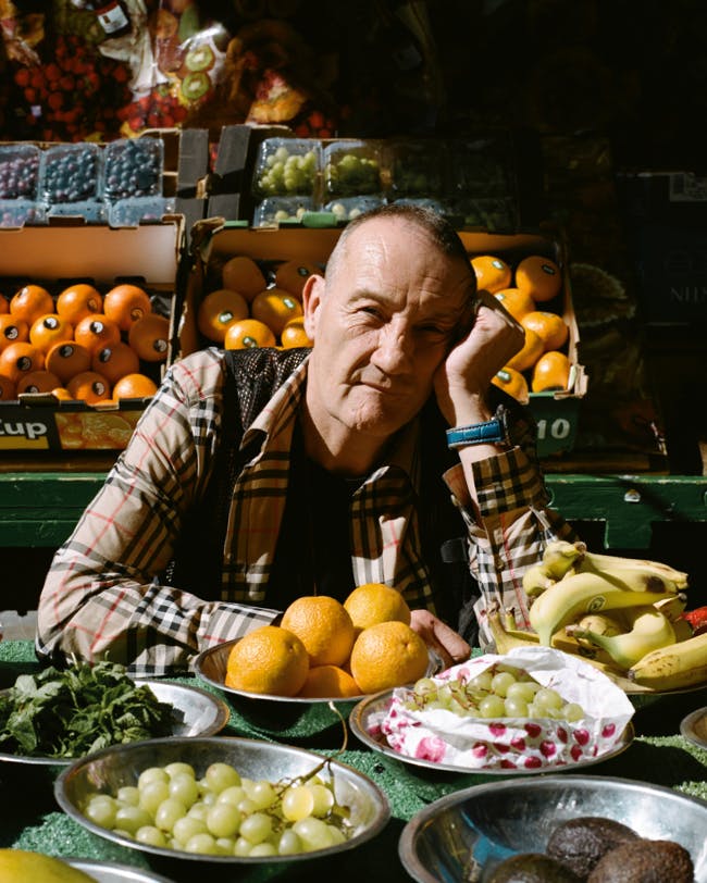 A man sitting between various bowls of fruit.