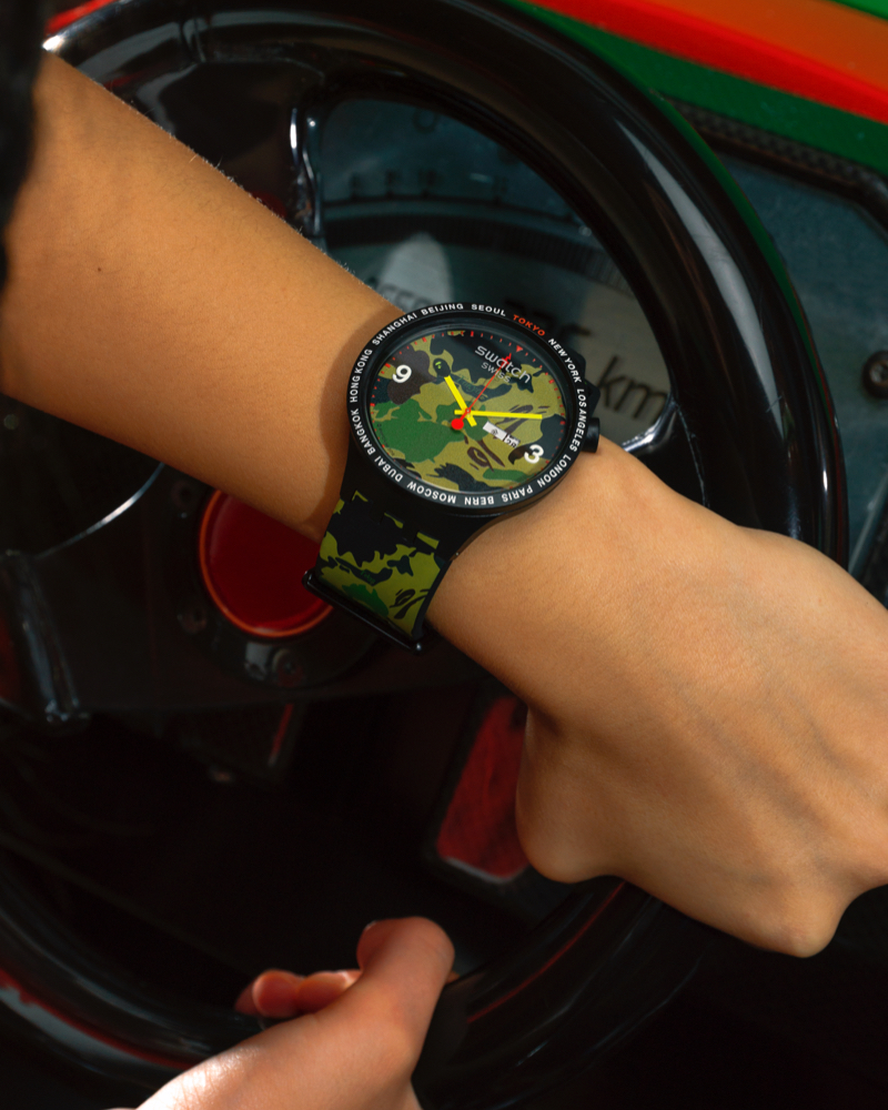Close up of an arm wearing a swatch x bape watch.
