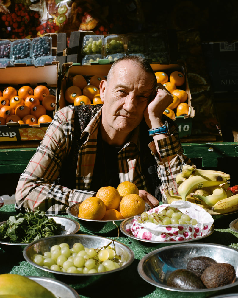 A man sitting between various bowls of fruit.