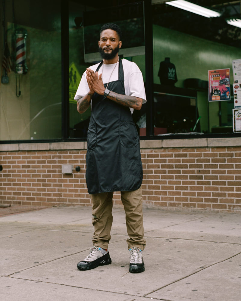 A man standing in front of a barber shop.