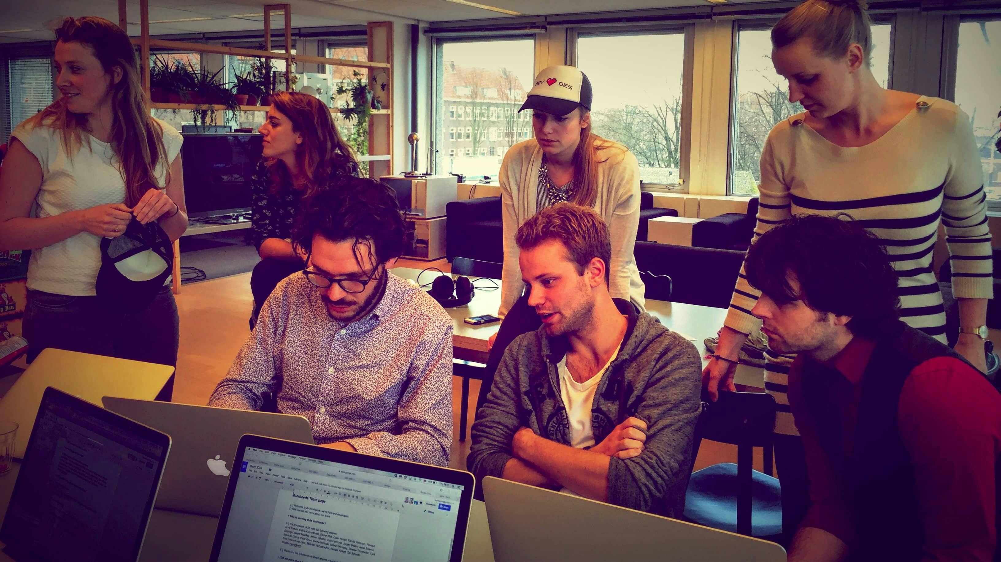 A group of 7 men and women working together on laptops