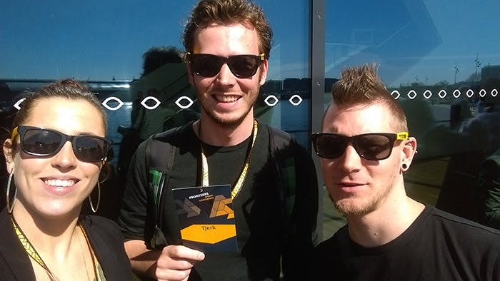 A woman and two men smiling into a camera all wearing sunglasses