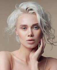 Beautiful woman with white hair touching her lower face with her hand