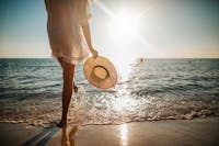Below the waist shot of a woman standing on the beach.