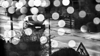 A street scene on a rainy night with car on road, reflections and bokeh effect 
