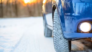 Blue Car with Winter Tires on the Snowy Road