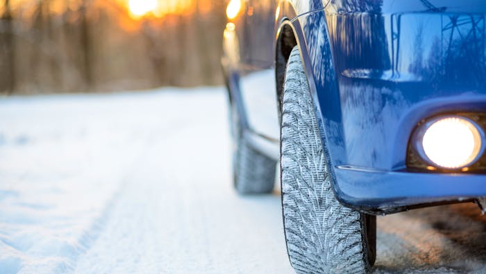 Blue Car with Winter Tires on the Snowy Road