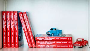 Books in a bookshelf with toy cars