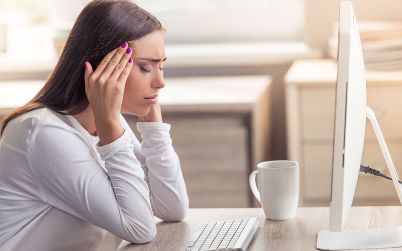 woman with a headache while sitting in front of a computer