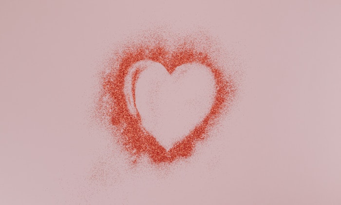Love heart in red glitter on a pink background