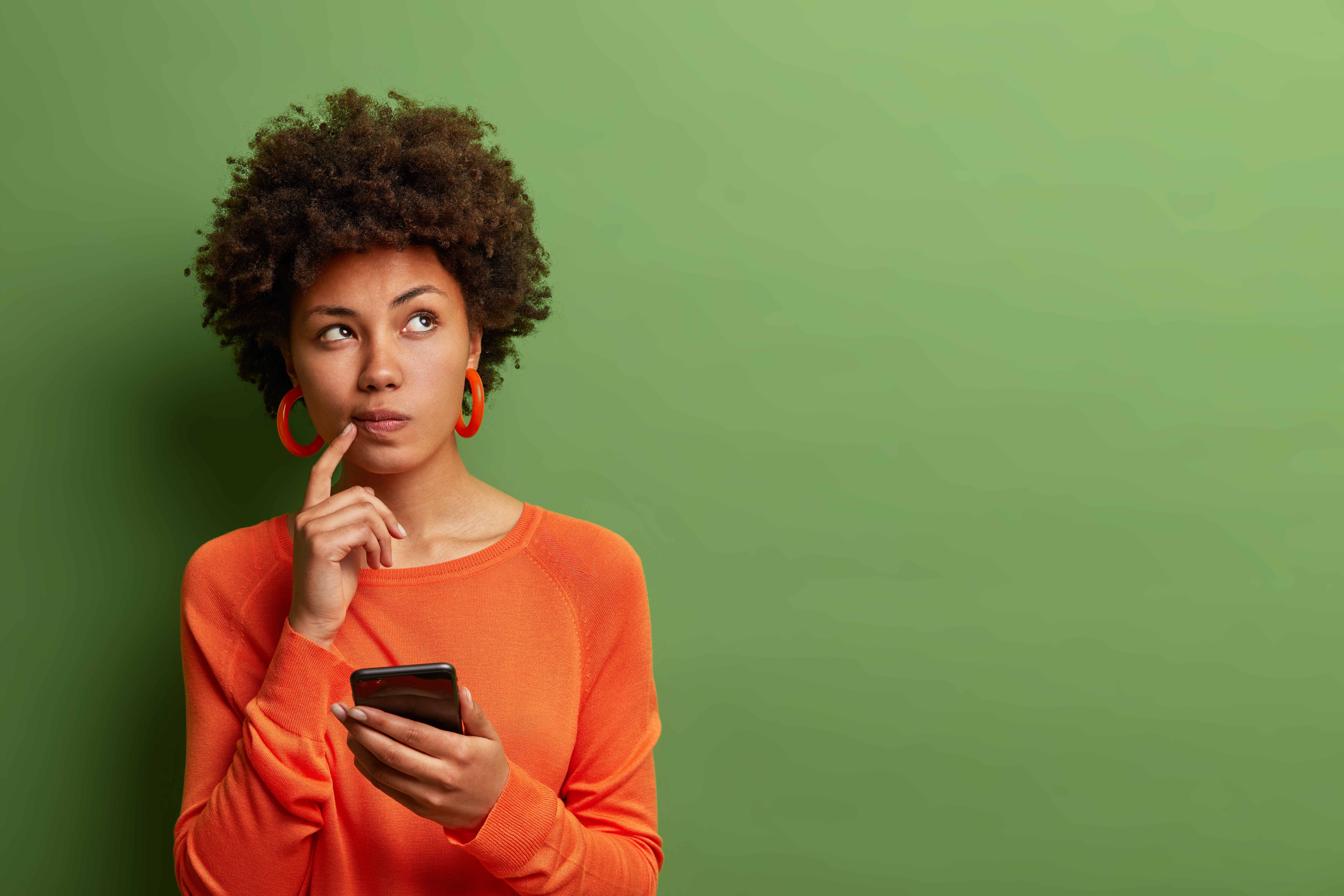 Woman thinks deeply about something and uses modern mobile phone