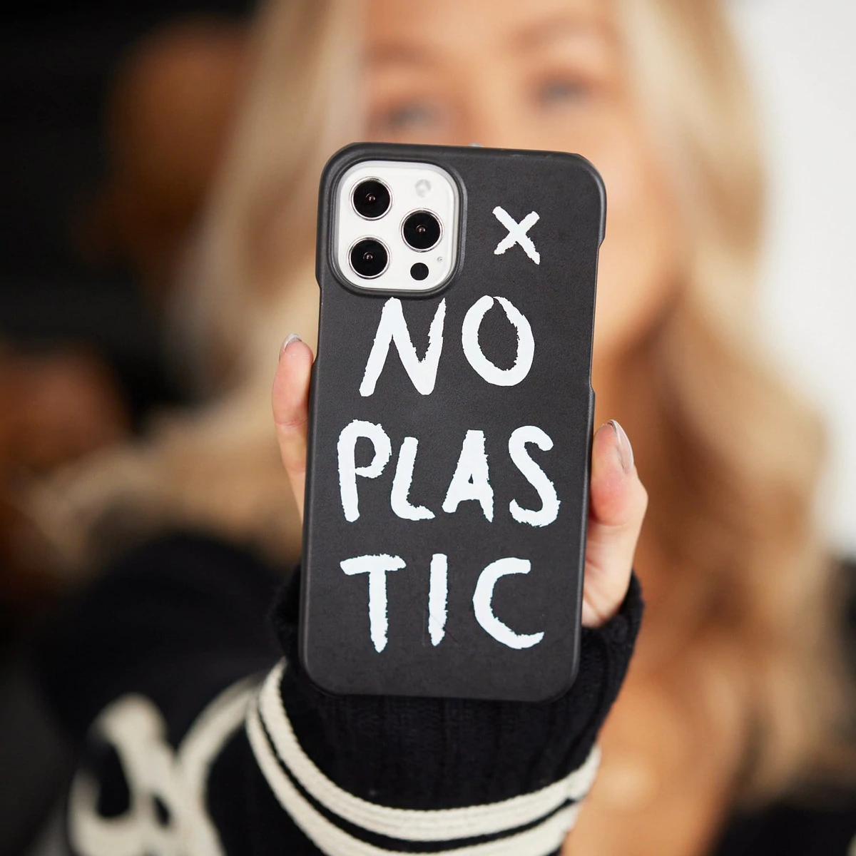 a woman holding an iphone in a plastic-free case