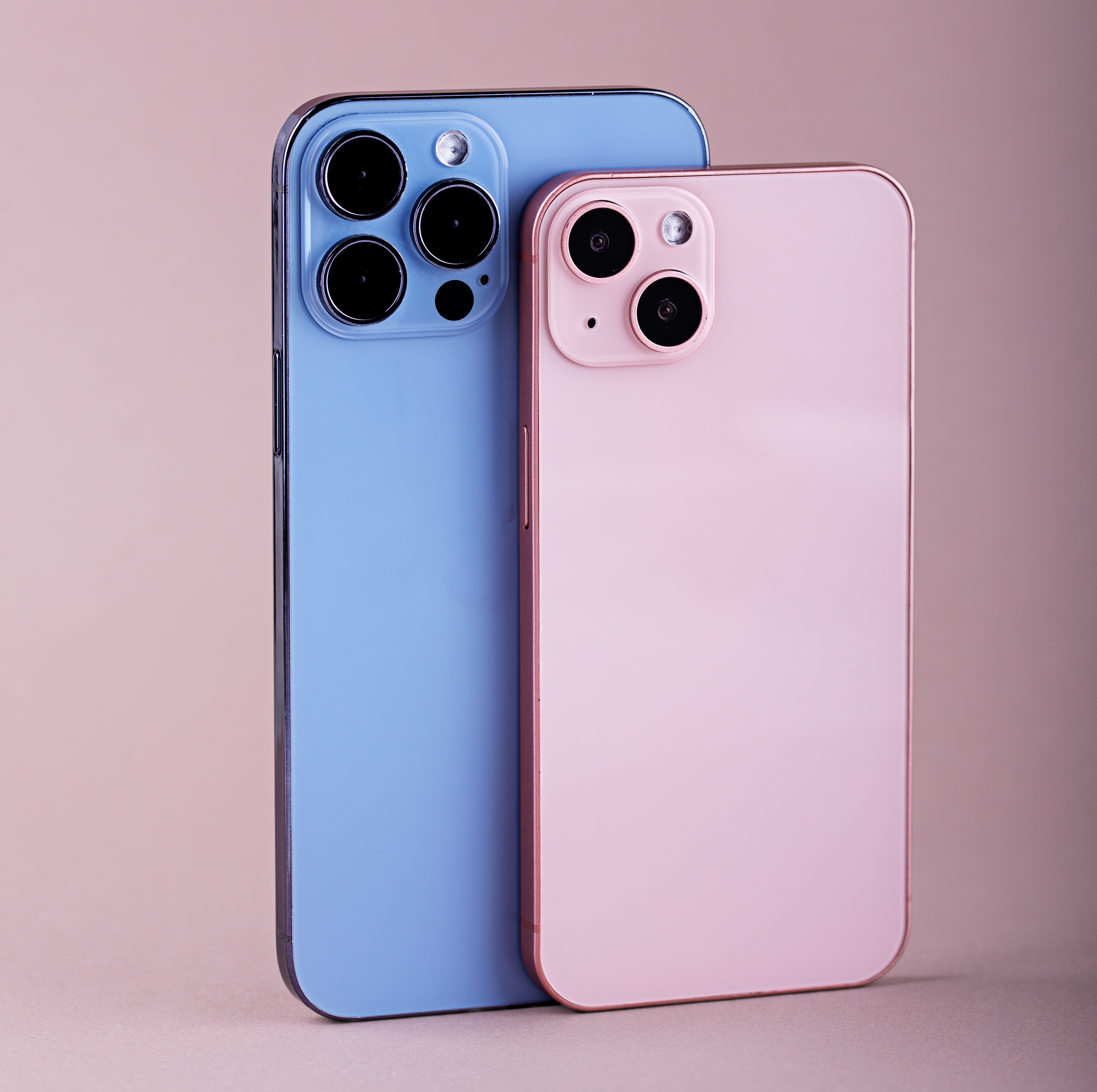 two smartphones standing up on a pink background