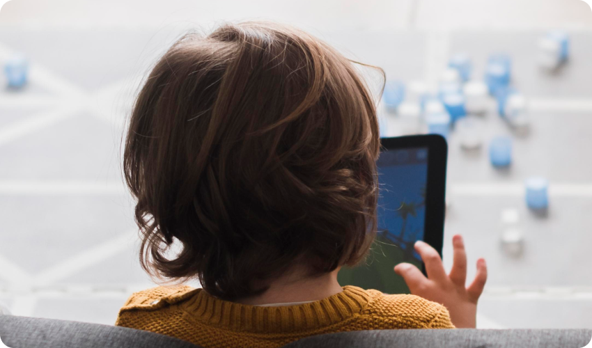 back view of child holding electronic tablet