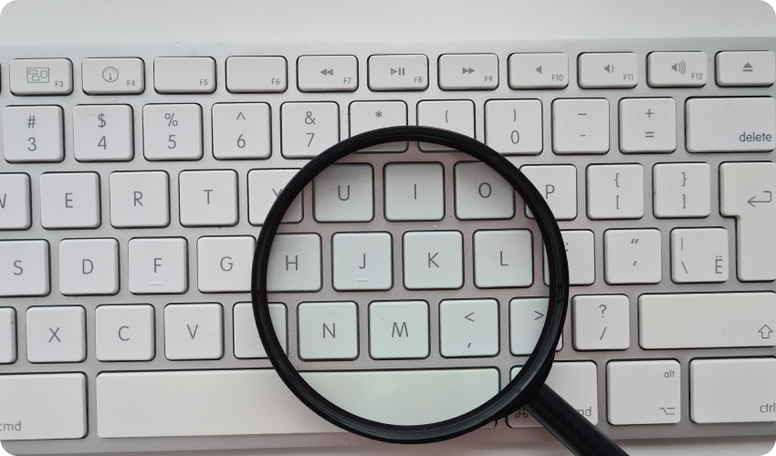 Magnifying glass over a keyboard to symbolise researching online