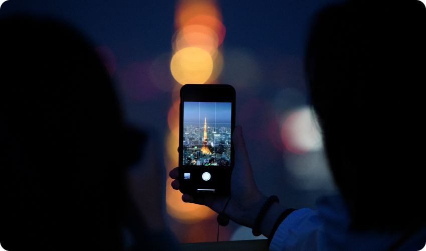 Person taking a picture of the Tokyo Tower Japan at night using a mobile phone