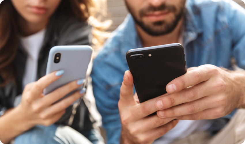 Couple sitting on stairs outdoors using mobile phones