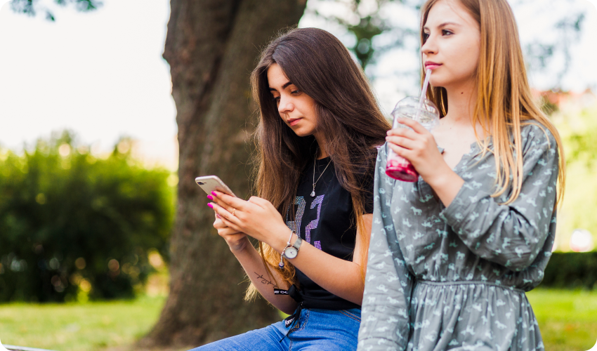 Girl being ignored by her friend who is texting on a phone.