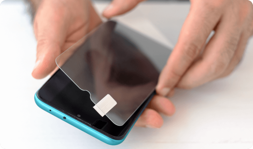 Man applying a protective tempered glass screen onto his phone