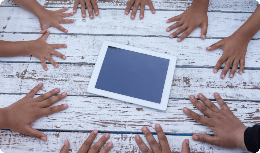 Childrens hands around iPad Little Lives uk charity