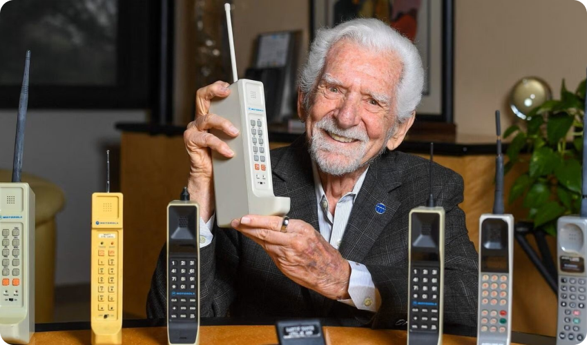 an old man holding a prototype mobile phone