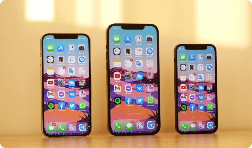 three models of iphones standing upright with home screen on the display