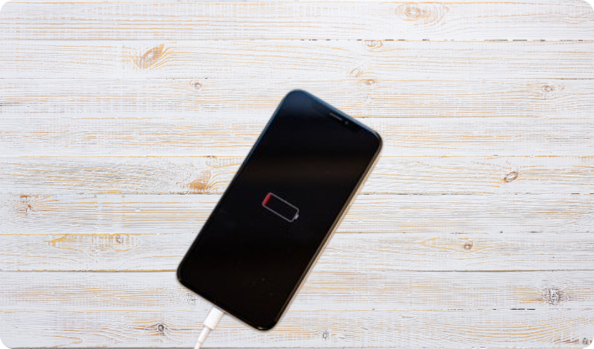 iPhone with low battery charging on a table.