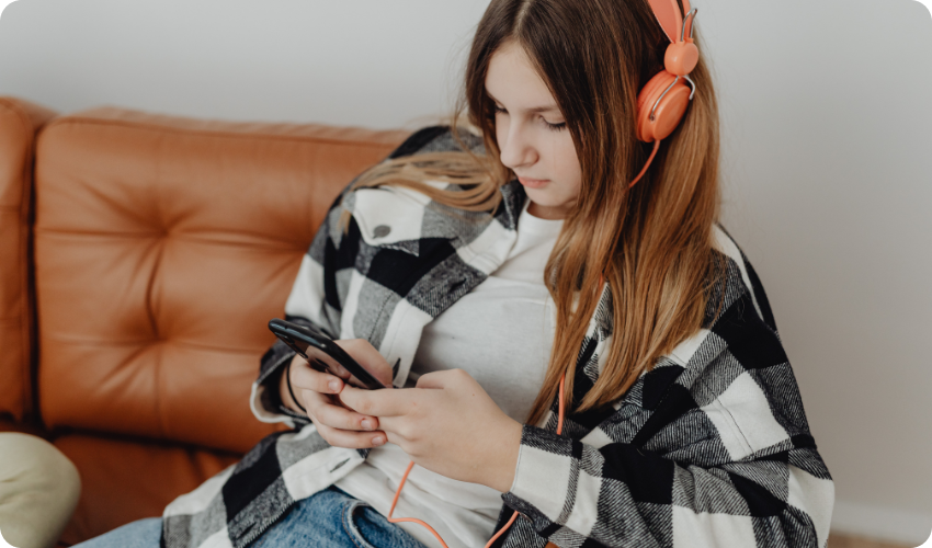 Girl listening to music on wired headphones plugged in to phone.