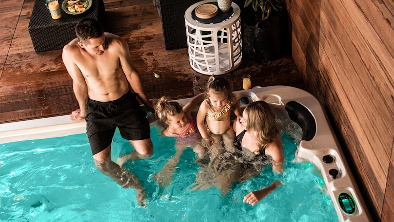 Family relaxing in aqualounge swim spa