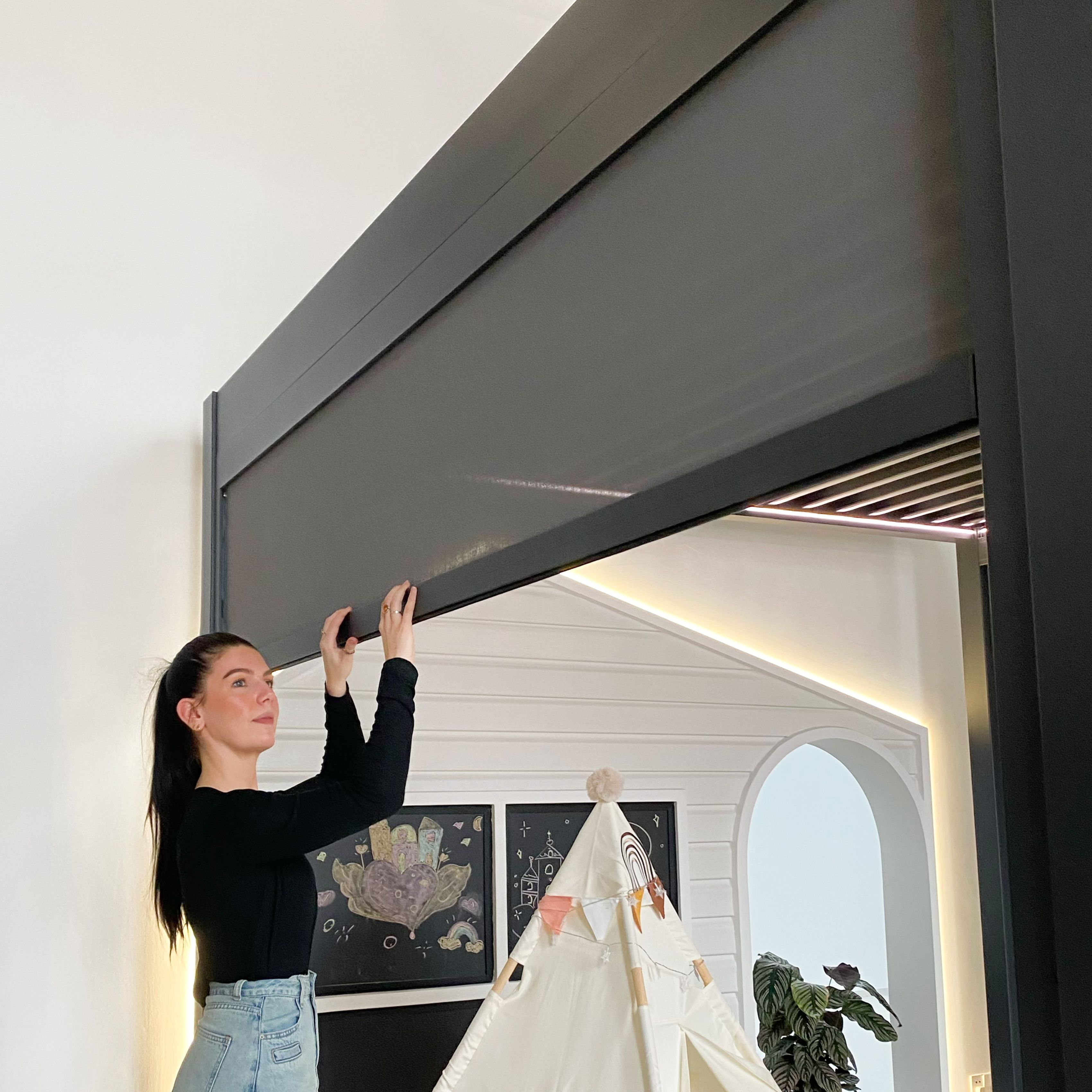A woman adjusting the Vortex pergola zip track blind