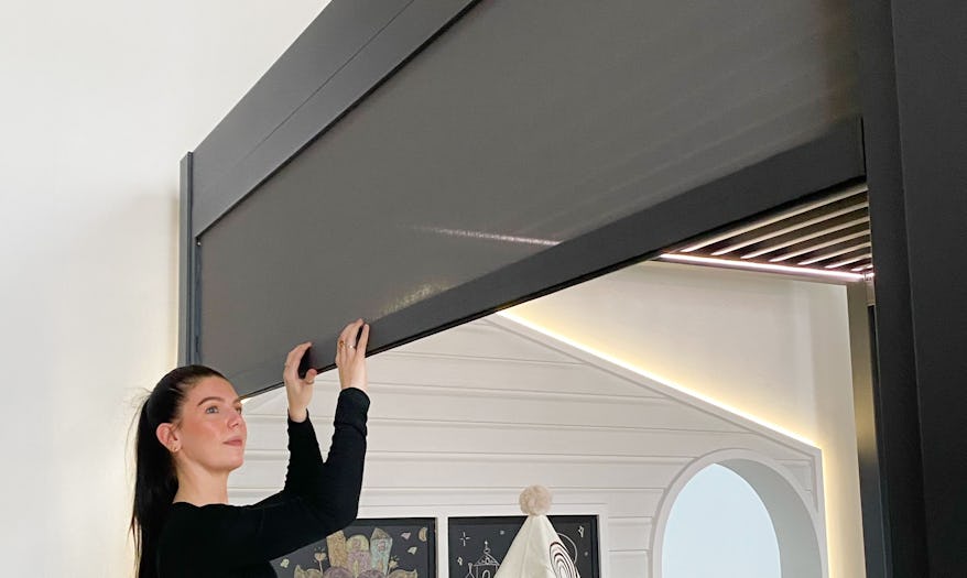 A woman adjusting the Vortex pergola zip track blind