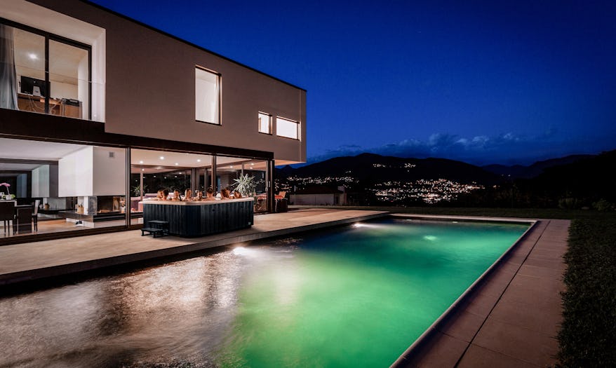 A group of people relax in the Vortex Spas Titanium, enjoying hydrotherapy jets in a stylish outdoor setting with warm ambient lighting.