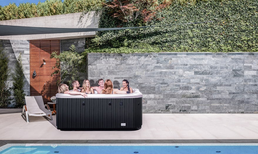 Group of 6 friends enjoying on a Cobalt spa pool that is beside a large pool