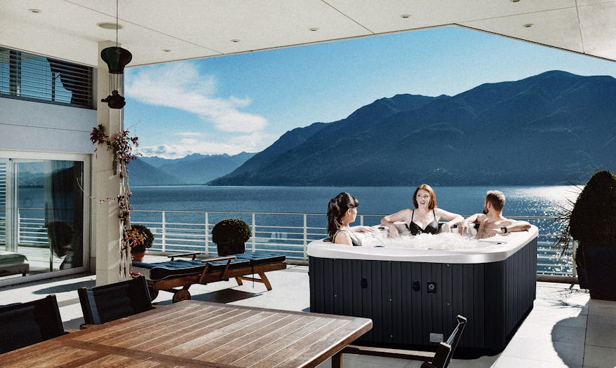 Three friends enjoying soaking on a Neon spa pool overlooking a scenic lake and mountain view