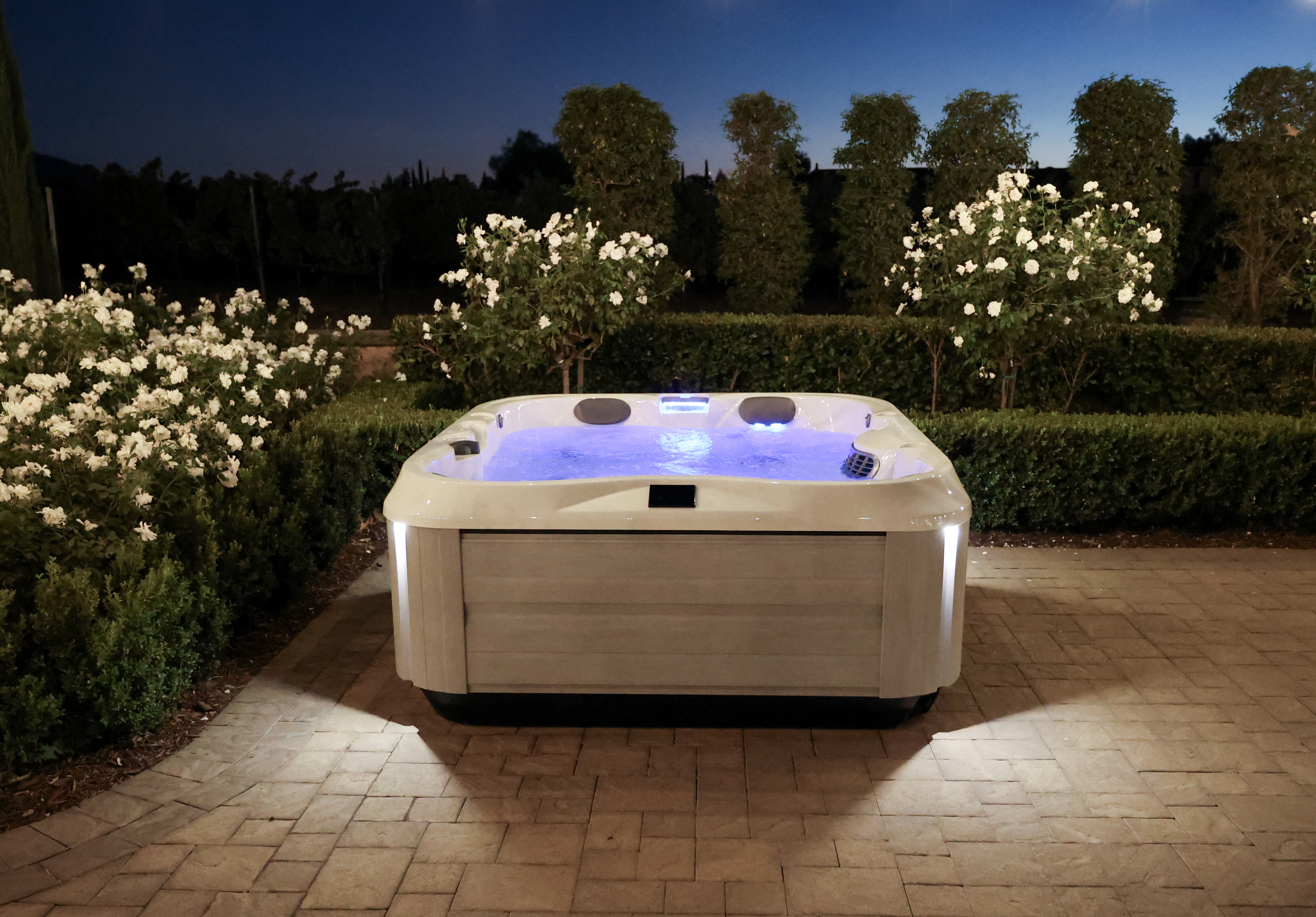 Night view of a backyard with a J-325 hot tub