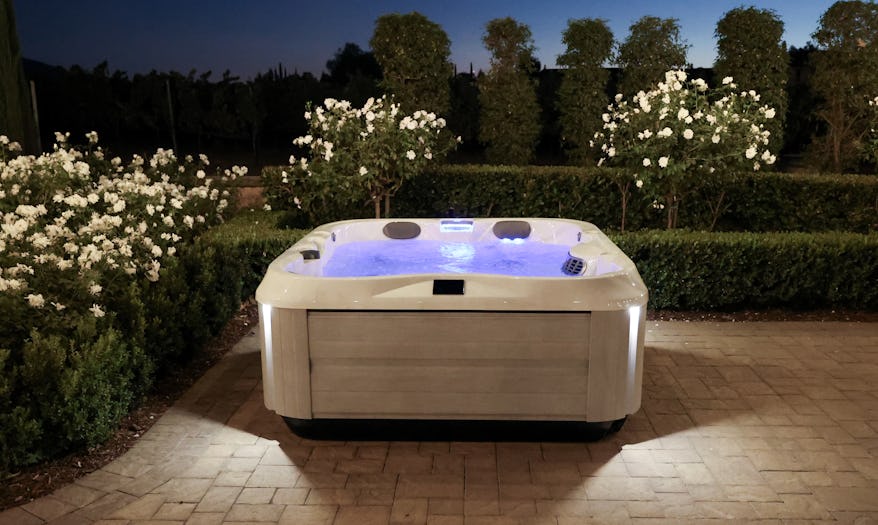 Night view of a backyard with a J-325 hot tub