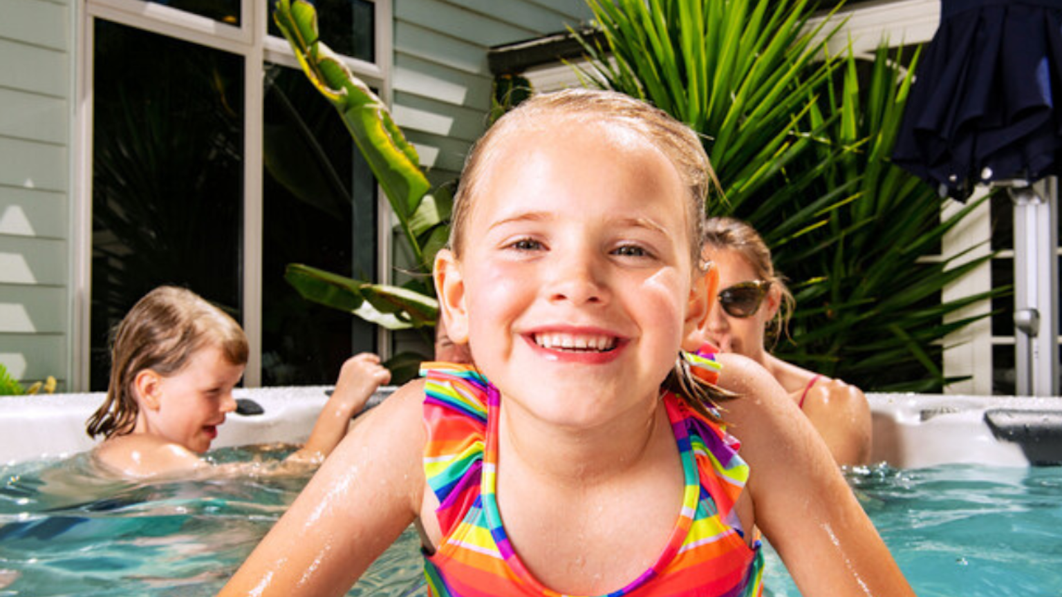 A girl happily smiling in a spa pool with her family