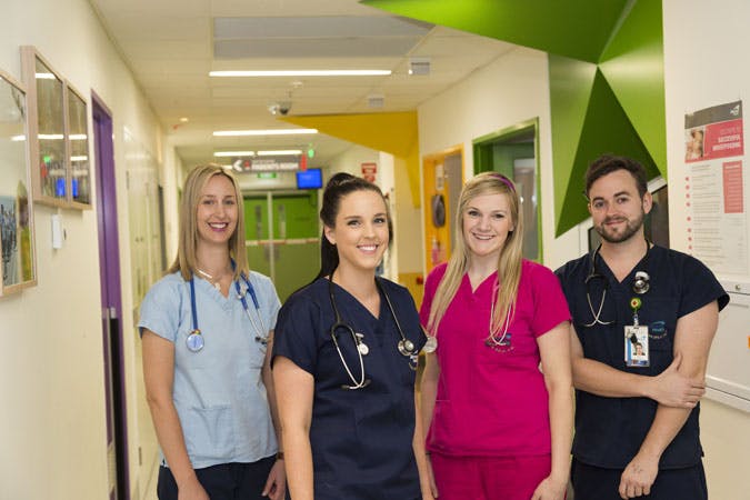 Four nurses standing in a hospital hallway