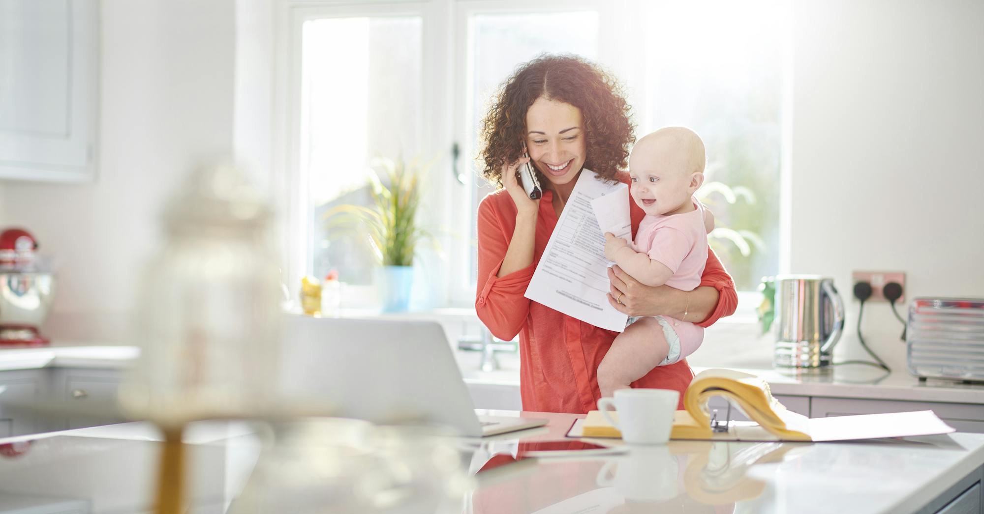 woman in kitchen paying a bill on her phone