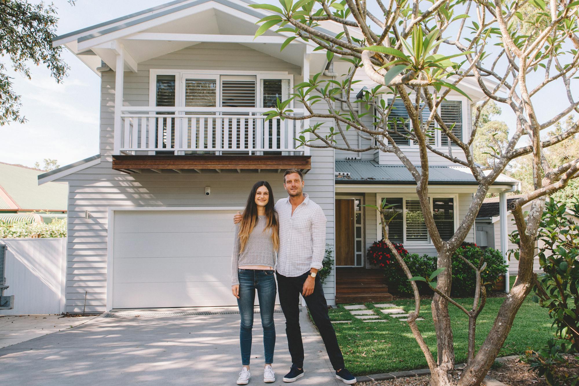 Happy couple standing in front of their home