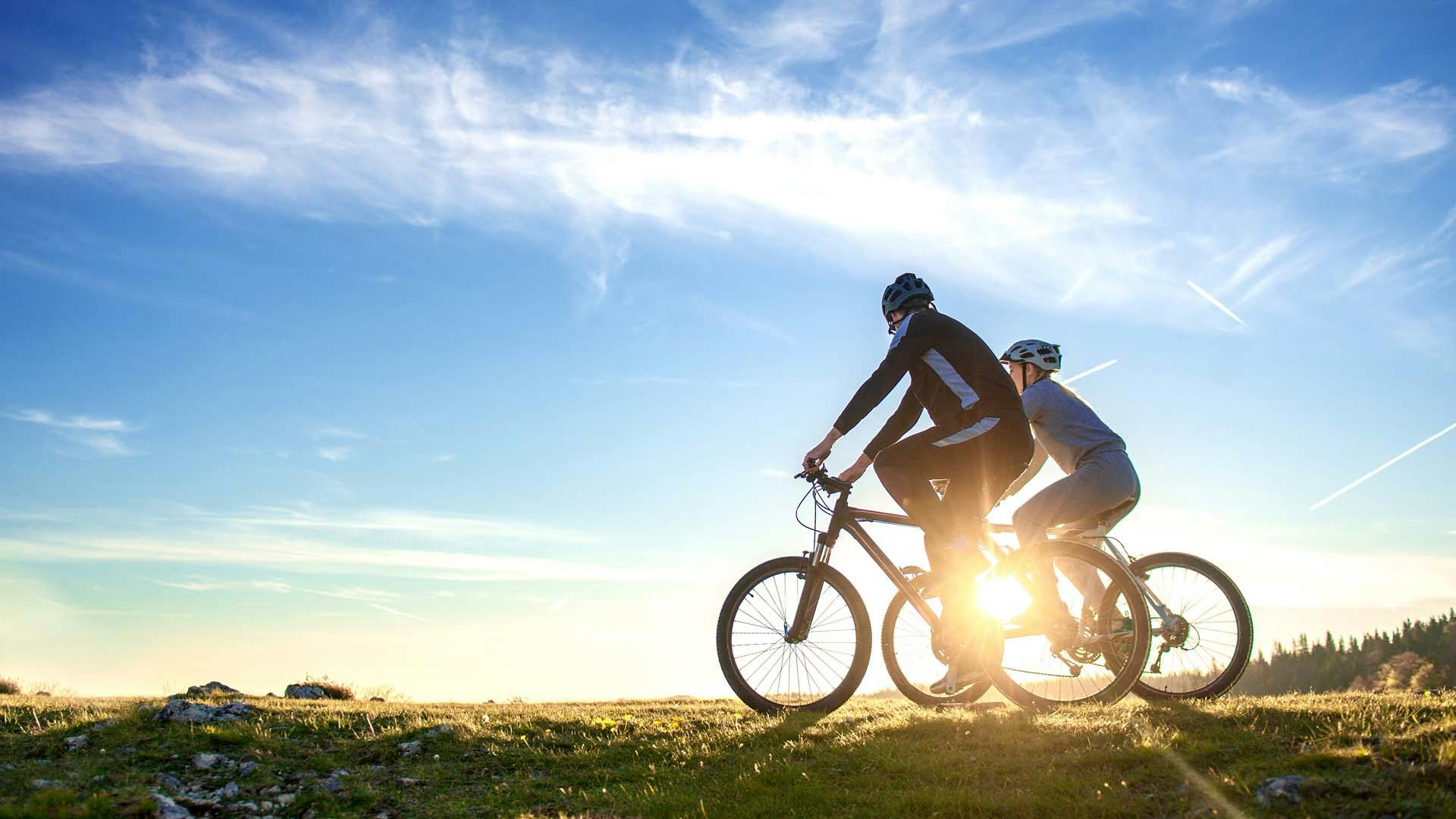 Financial freedom - Happy mountain bike couple outdoors have fun together on a summer afternoon sunset.