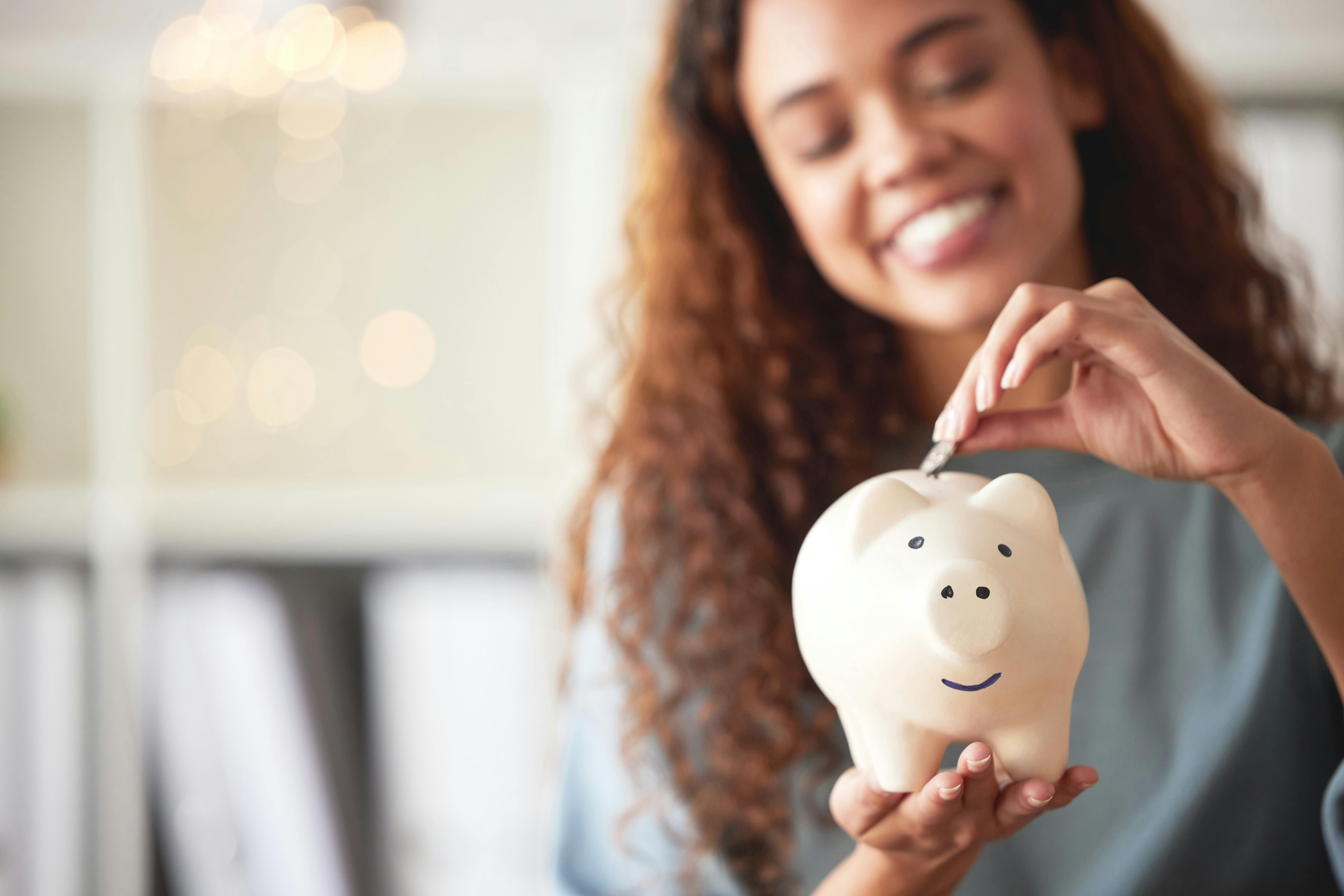Woman putting coin into piggy bank